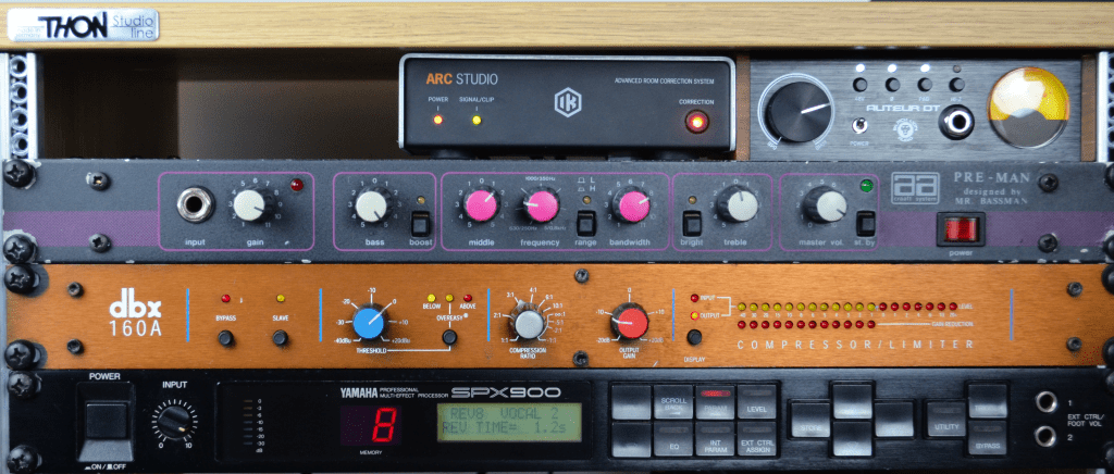 Top center shows an IK Multimedia ARC 4, to the right is a Black Lion Audio Auteur DT microphone preamp. Below is a vintage rack-mounted bass amplifier, followed by a dbx 160a compressor and an SPX 900 effects processor